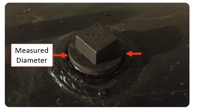 A heating oil tank plug with arrows showing where to measure across its outside edge